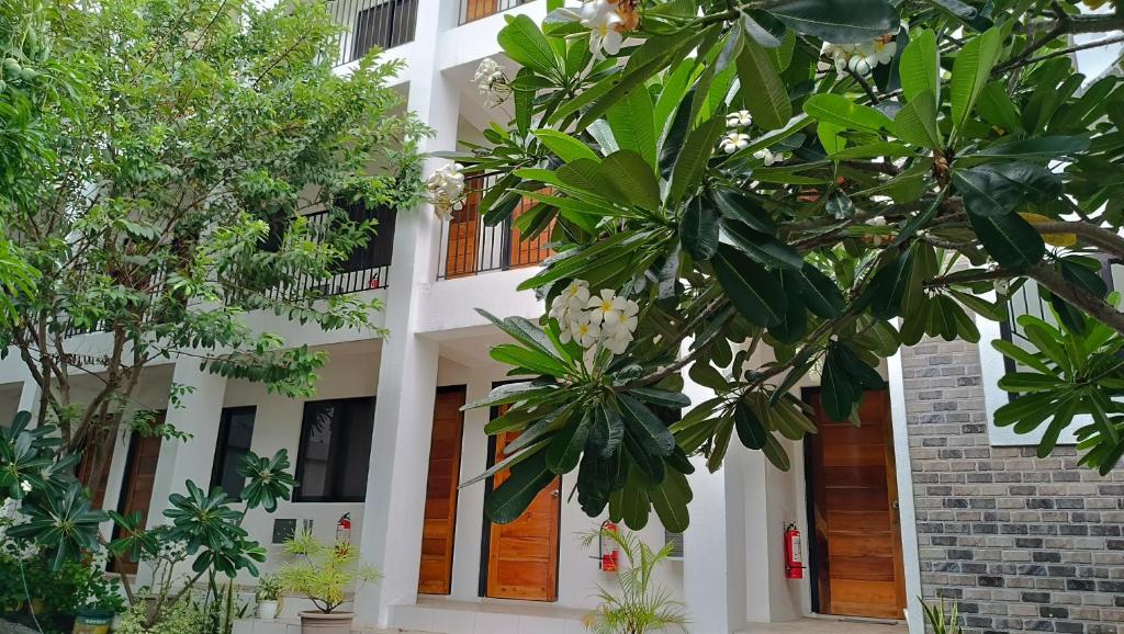马尼拉The Palines Apartment and Guesthouse - Vista Alabang的前面有树木的白色建筑