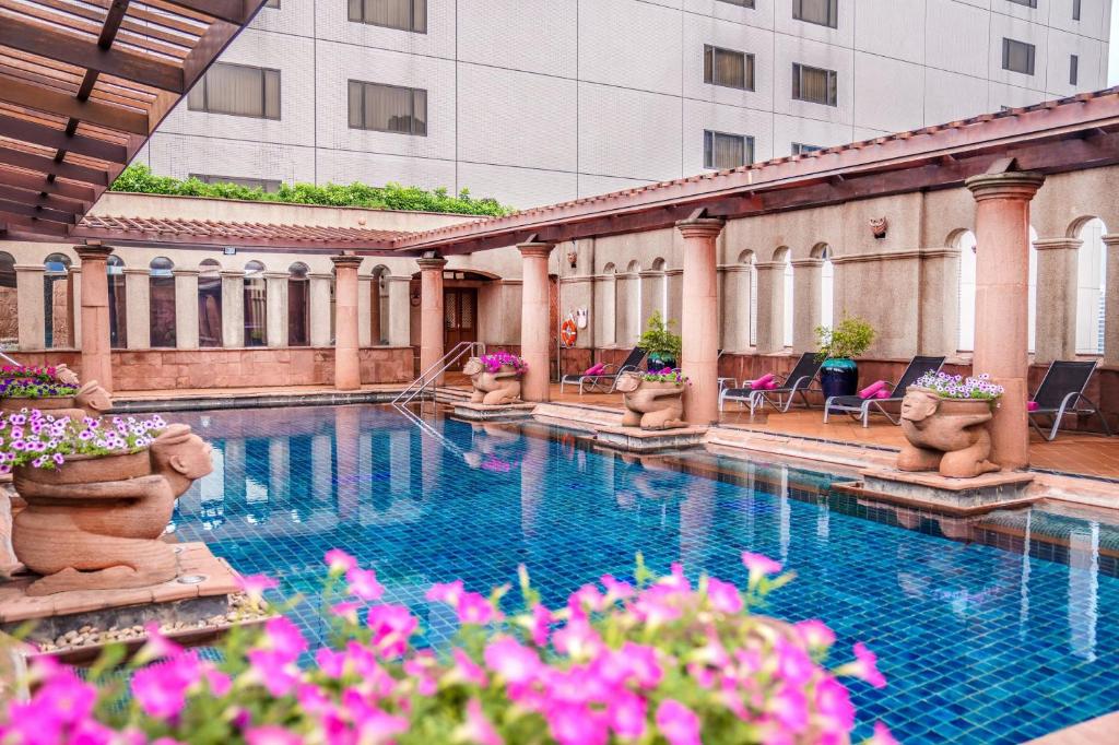 曼谷Crowne Plaza Bangkok Lumpini Park, an IHG Hotel的一座游泳池,位于一座粉红色花的建筑中