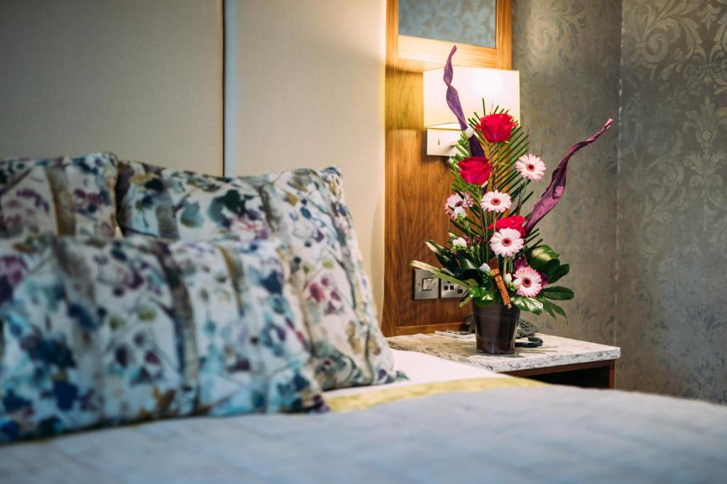 五英里镇The Valley Hotel & Carriage Gardens的一张带枕头的床和一张桌子上的花瓶
