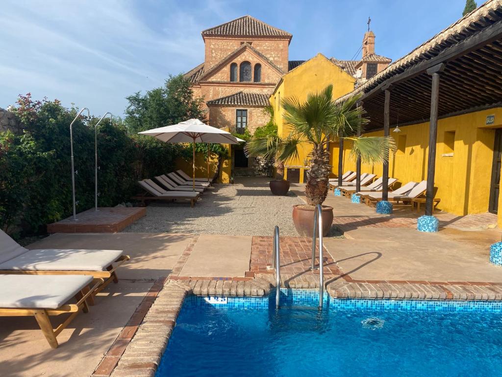 阿尔沃洛特Hotel Cortijo del Marqués的一个带躺椅的游泳池和一个带教堂的建筑