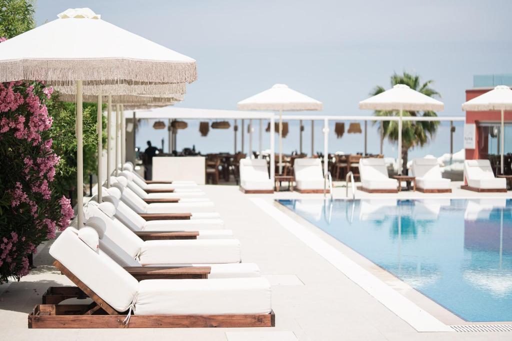 波利克罗诺Ikyma Boutique的酒店游泳池设有白色躺椅和遮阳伞