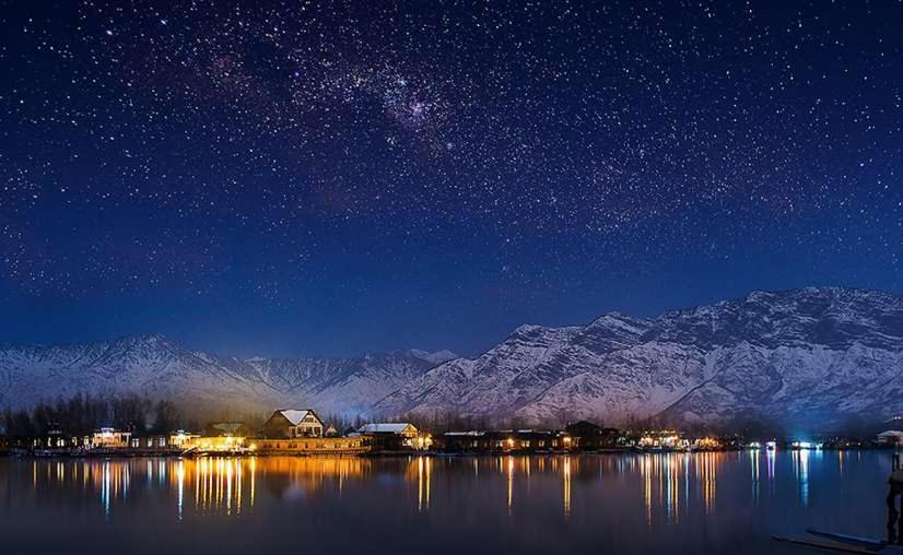 斯利那加Gulshan Group of HouseBoat的在一个以山为背景的湖泊上度过的星空之夜