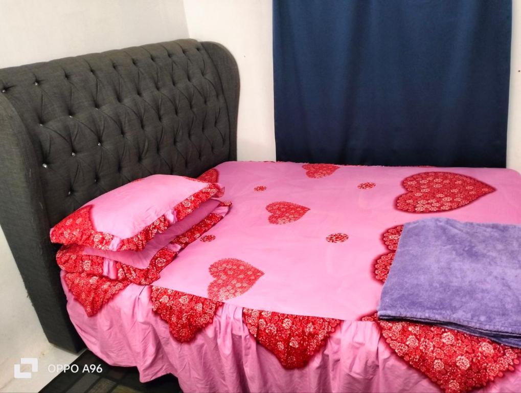 话毛生Homestay Saujana Harmoni D'Petron的一张带粉红色床单的床,上面有红心