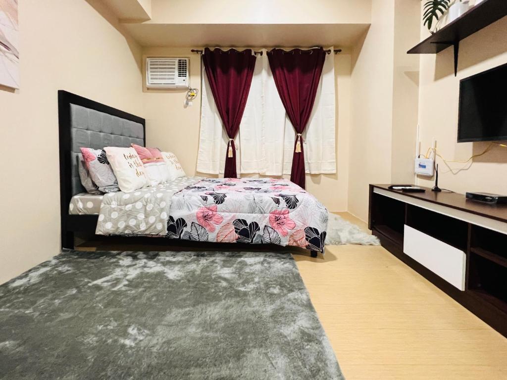 伊洛伊洛* *K Irresistable value for 3的一间卧室配有一张带窗帘的床和电视。