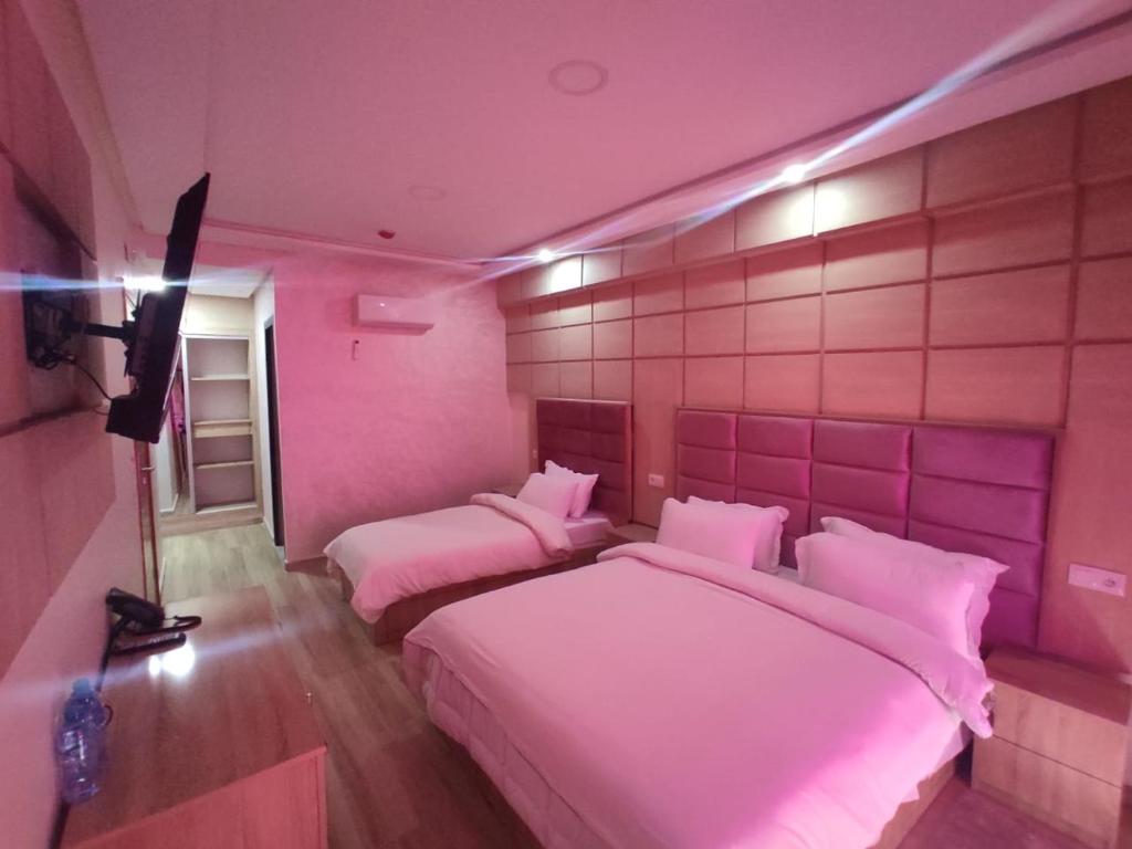 梅克内斯FEKRI HOTEL的粉红色客房内的两张床和粉红色的灯光