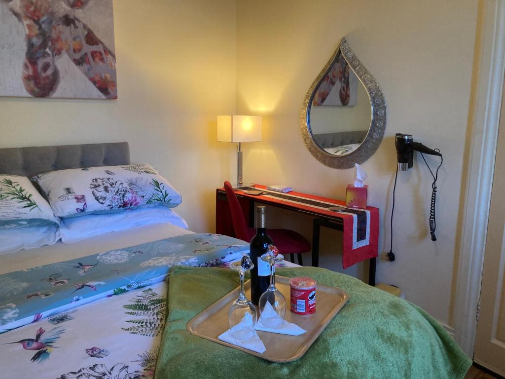 贝尔法斯特Mountroyal Victorian Studio Self Catering Apartment的一间卧室配有一张床和一个带一瓶葡萄酒的托盘