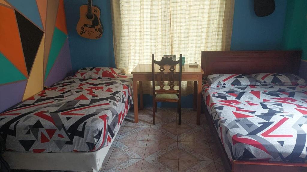 巴克里索莫雷诺港C.C. Habitaciones的一间卧室配有两张床和一张带吉他桌的桌子。