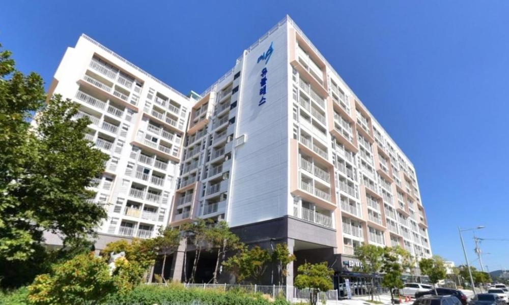 丽水市Myeongga Ubleth Hotel的停车场上高大的白色公寓楼