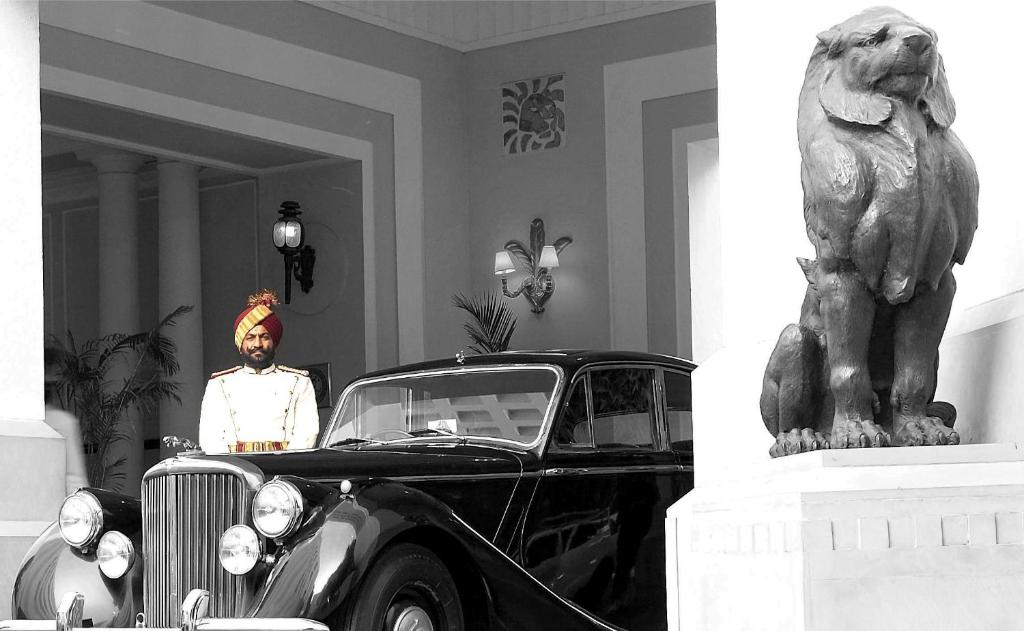 新德里新德里帝国酒店的站在雕像旁的老车旁的人