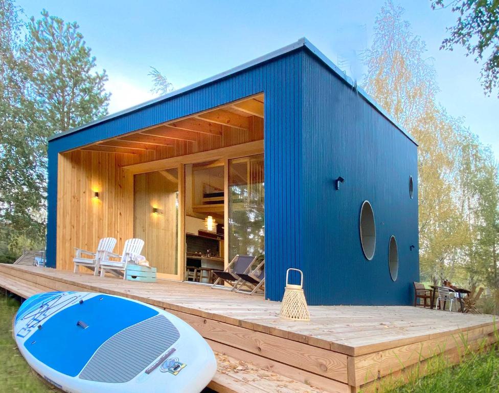BrzozieLunette Lodge am See mit Sauna für 10 Gäste的蓝色的房子,甲板上设有冲浪板