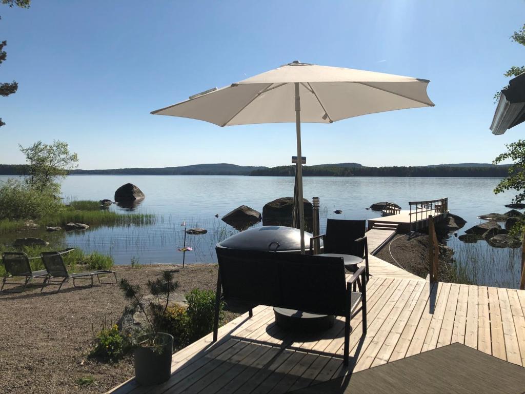 LeppälahtiKesämökki Tanela的湖畔甲板上的桌子和遮阳伞
