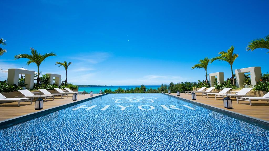 恩纳Hiyori Ocean Resort Okinawa的一个带躺椅的度假游泳池以及大海