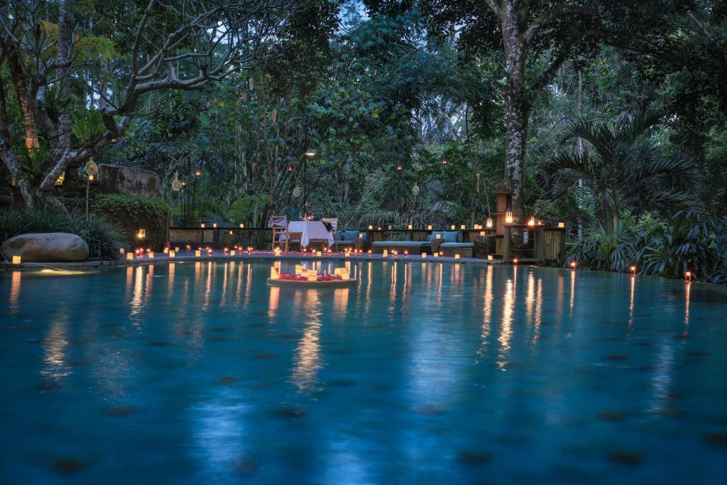 帕洋安Pramana Giri Kusuma的夜间游泳池,水中灯火通明