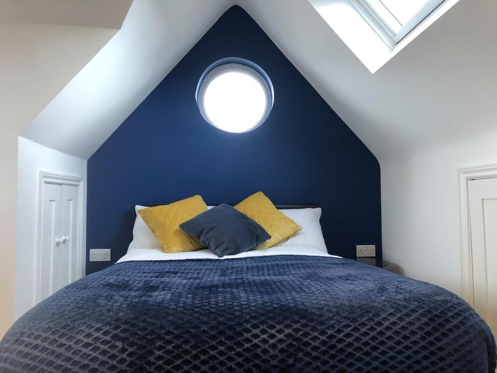 剑桥Cosy Loft Apartment Just Off Vibrant Mill Rd Cb1的蓝色卧室,配有一张带圆形窗户的床