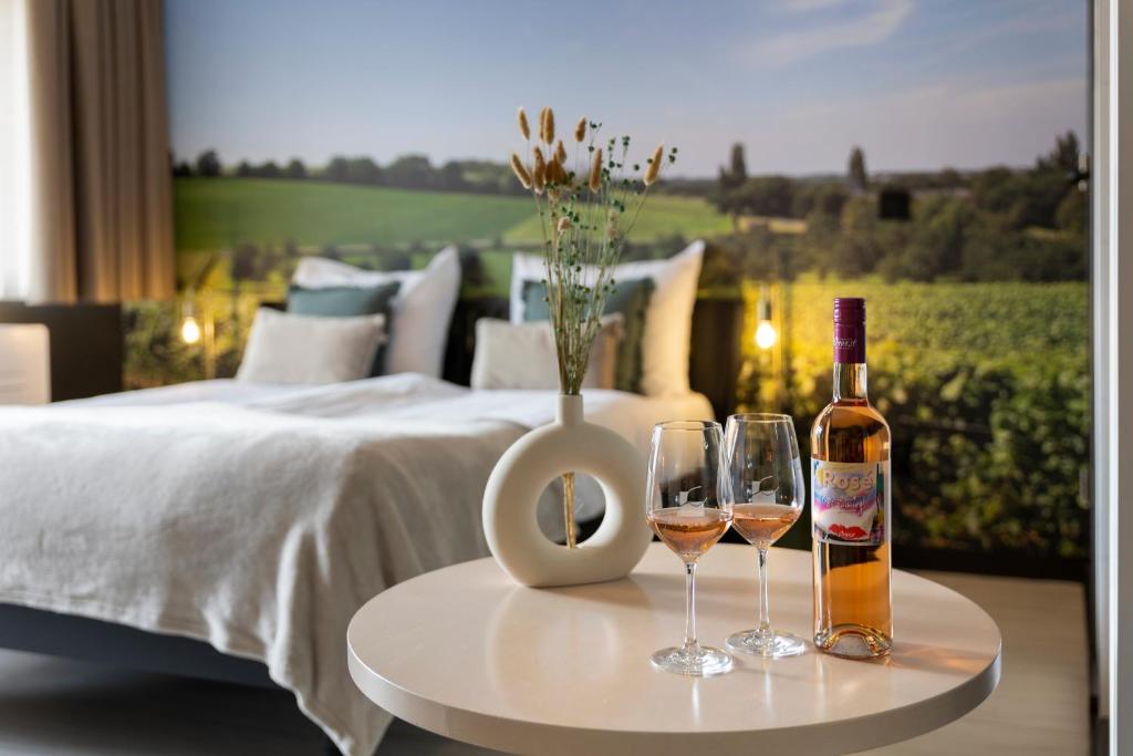 法尔肯堡Dormio Wijnhotel Valkenburg的两杯酒,放在床边的桌子上