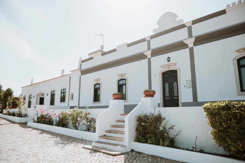 阿尔布费拉Cerca Velha - Country House的一排白色的建筑,有楼梯和鲜花