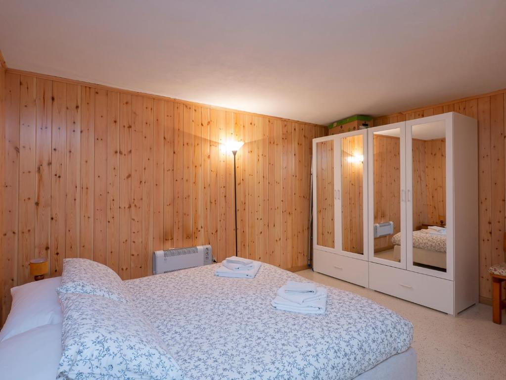 PiattaI Host Apartment - Centrale 18 - Bormio的卧室设有白色的床和木墙