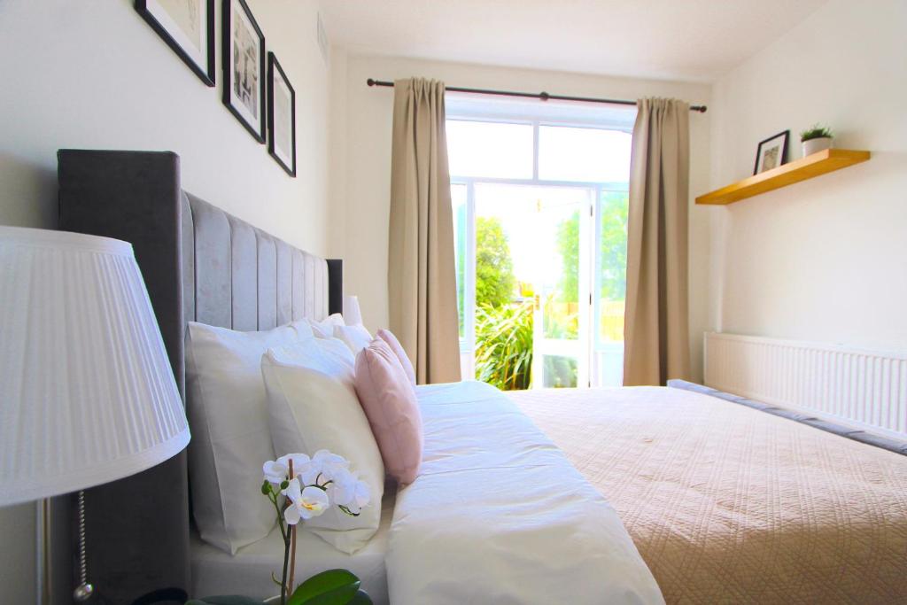 伦敦Beautiful one bed garden flat in Muswell hill的卧室配有带白色枕头的床和窗户。