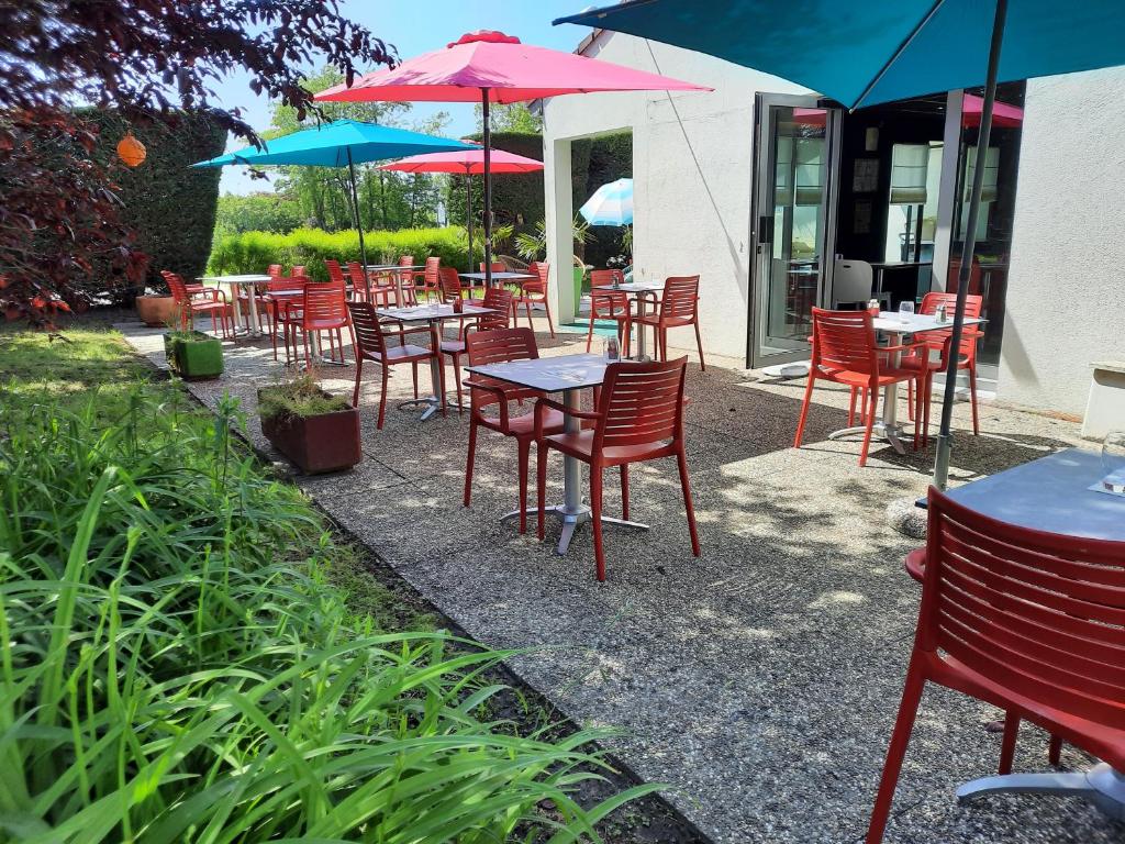 梅斯Campanile Metz Est Technopole - Restaurant的一组桌椅和遮阳伞