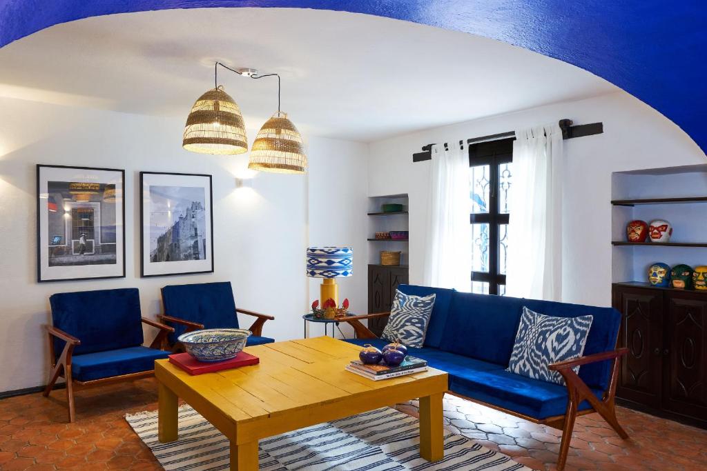 墨西哥城AmazINN Places Casa Coyoacan的客厅配有蓝色的沙发和木桌