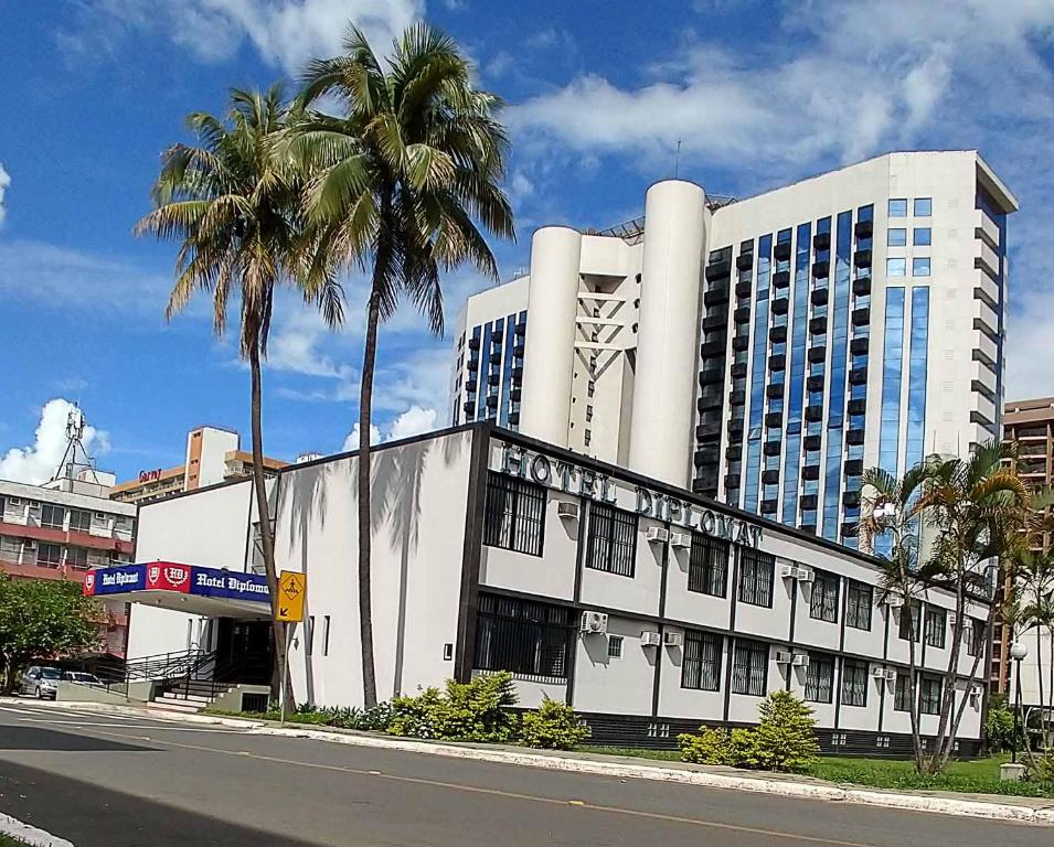巴西利亚大使酒店的一座白色的大建筑,前面有棕榈树