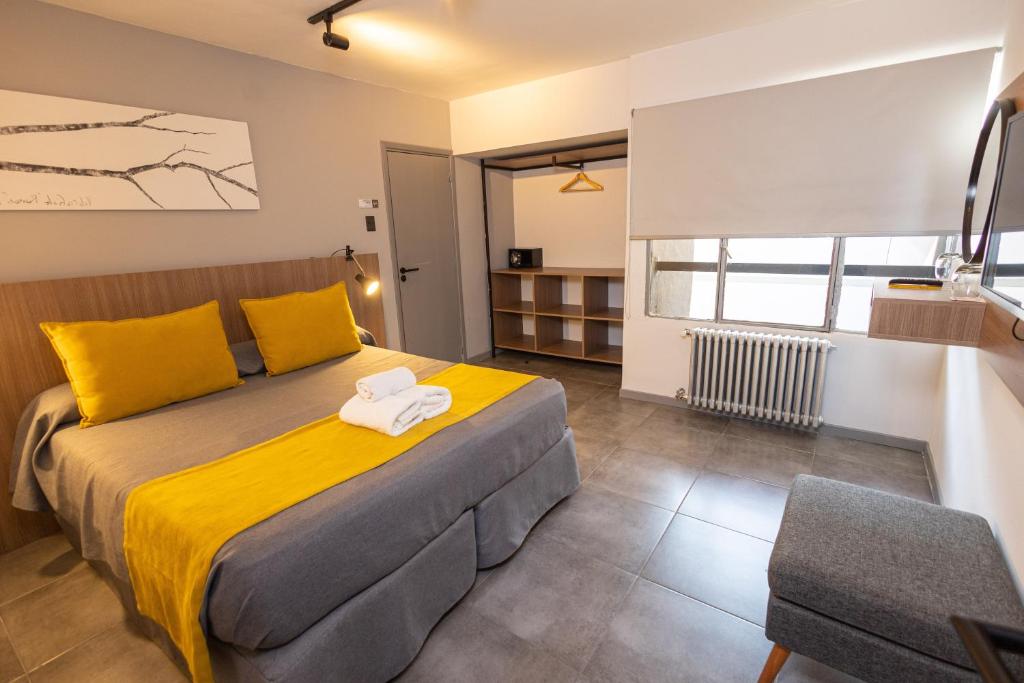 圣卡洛斯-德巴里洛切HOTEL CONCEPT BARILOCHE的一间卧室配有一张带黄色枕头的大床