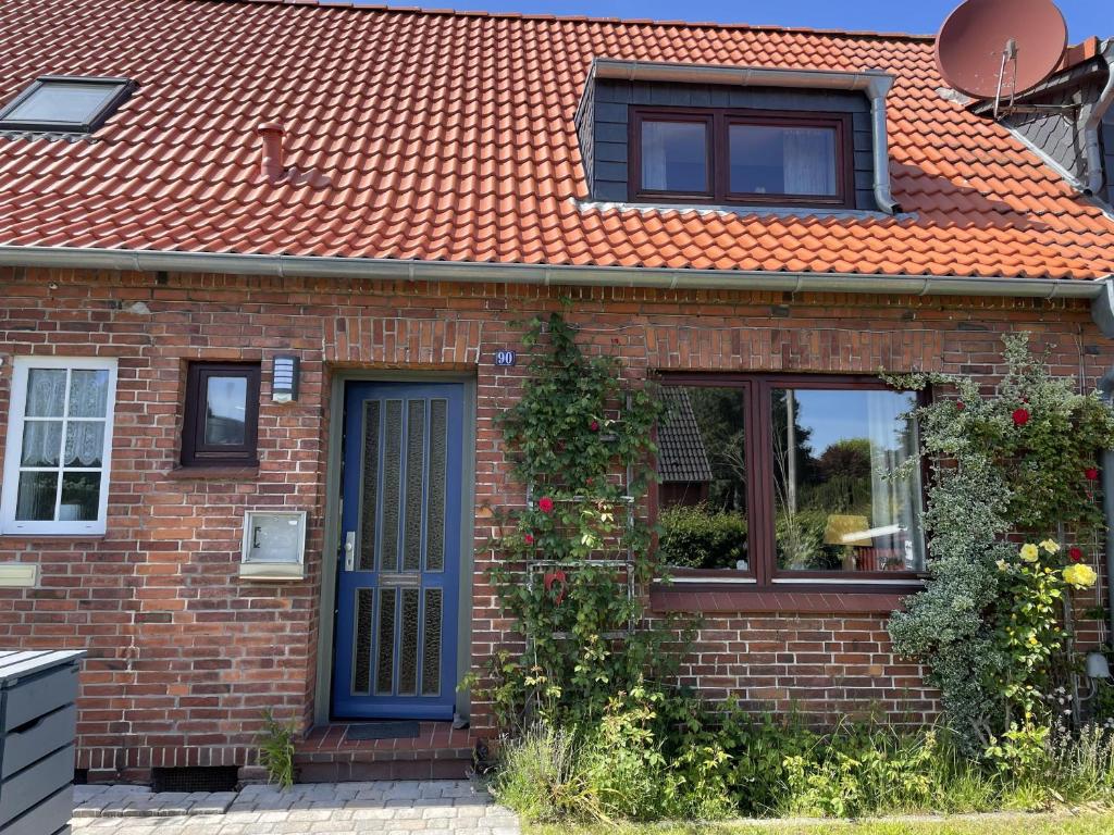 弗伦斯堡Ferienhaus Jenny的一座砖房,有橙色的屋顶和蓝色的门
