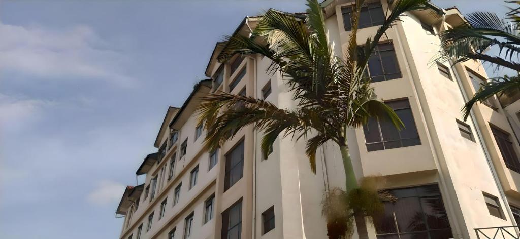 内罗毕Plus254 Hotel的一座高大的建筑,前面有一棵棕榈树