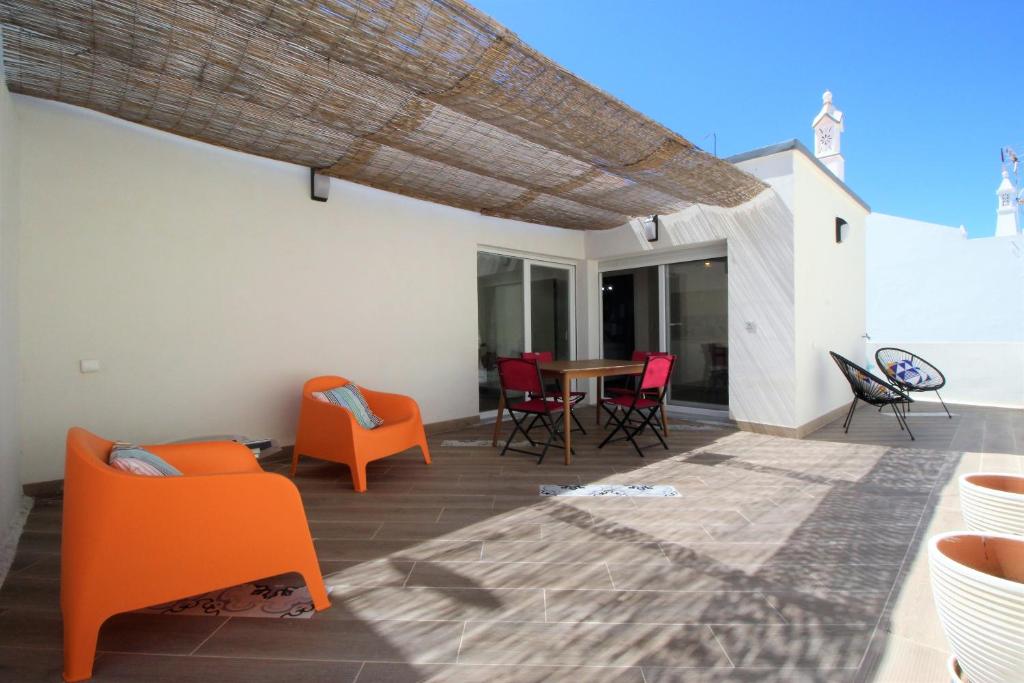 卡巴纳斯·德·塔维拉Mimosa House Cabanas的庭院配有橙色椅子和木桌
