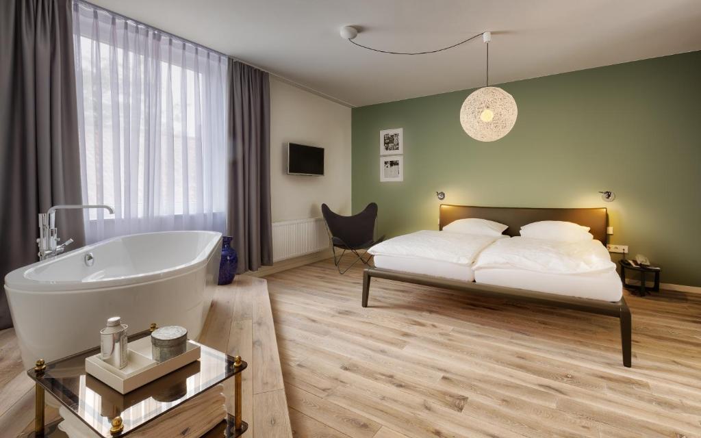 格伦察-维伦Das Eckert - Lifestyle Design Hotel & Fine Dining bei Basel (Grenzach)的一间卧室配有一张床、一个浴缸、一张床和一个浴缸