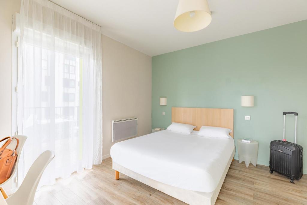 图尔图尔舒适城市公寓酒店的卧室配有白色的床和行李箱