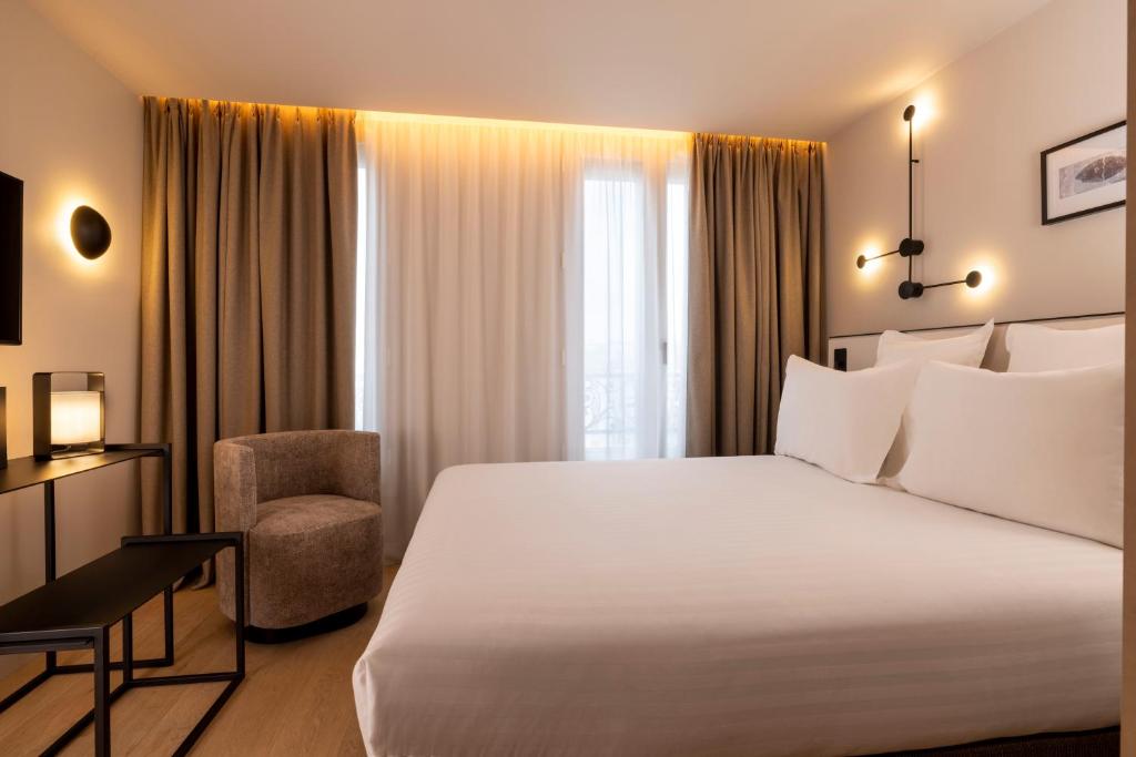 巴黎Hôtel Esté的卧室配有一张白色大床和一把椅子
