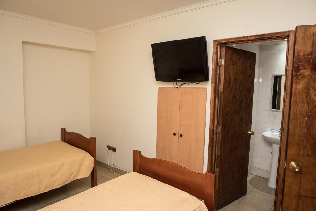 安托法加斯塔Hotel NIKYASAN的一间设有两张床和一台墙上电视的房间