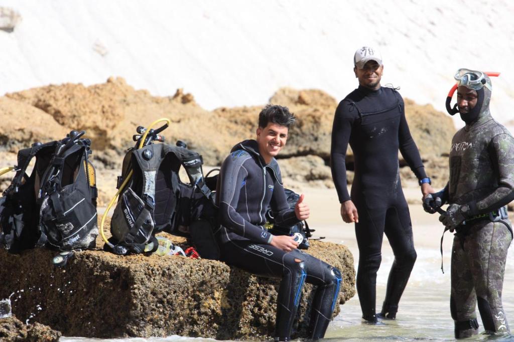 达赫拉DAKHLA DIVING CAMP的一群三人坐在水中的岩石上