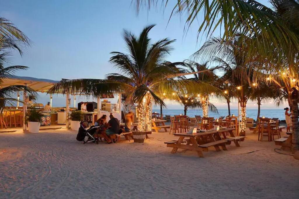 简蒂埃尔Dushi Apartment Near the Beach的一群人坐在海滩上,种着桌子和棕榈树