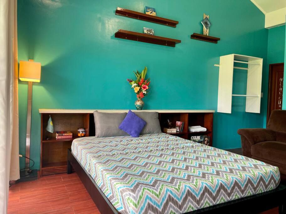 科罗尔Ngermid Oasis-Spacious Studio Loft W/ Garden Views的一间卧室配有一张蓝色墙壁的床
