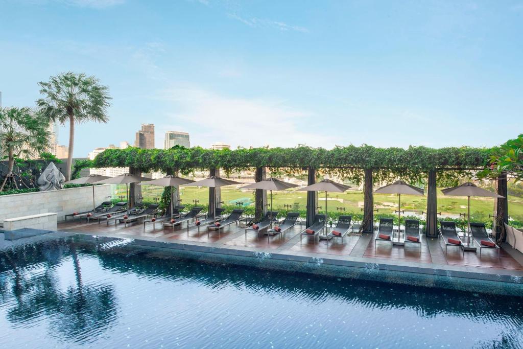 曼谷曼谷瑞吉酒店的水边带椅子和遮阳伞的游泳池