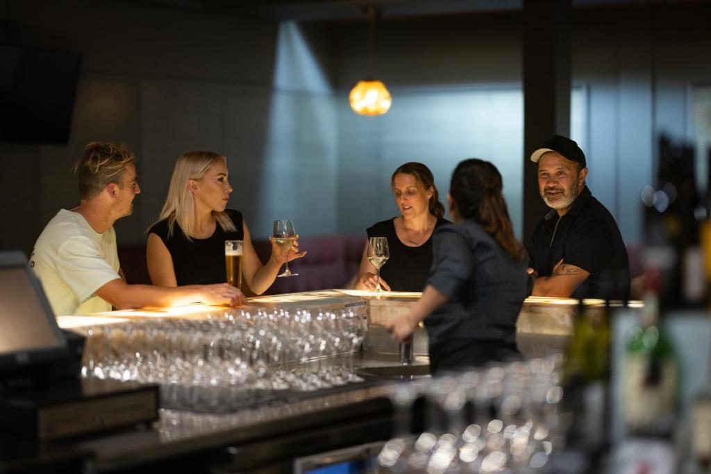 罗托鲁瓦罗托鲁阿千禧国际酒店的一群人坐在酒吧里,戴着酒杯