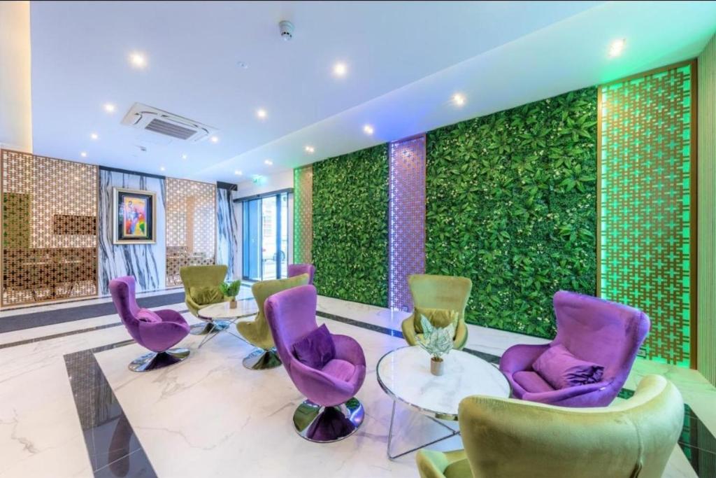 辛德尔芬根Hotel Business Bay das ehemalige Staycation Hotel的一间设有紫色椅子和绿色墙壁的客房