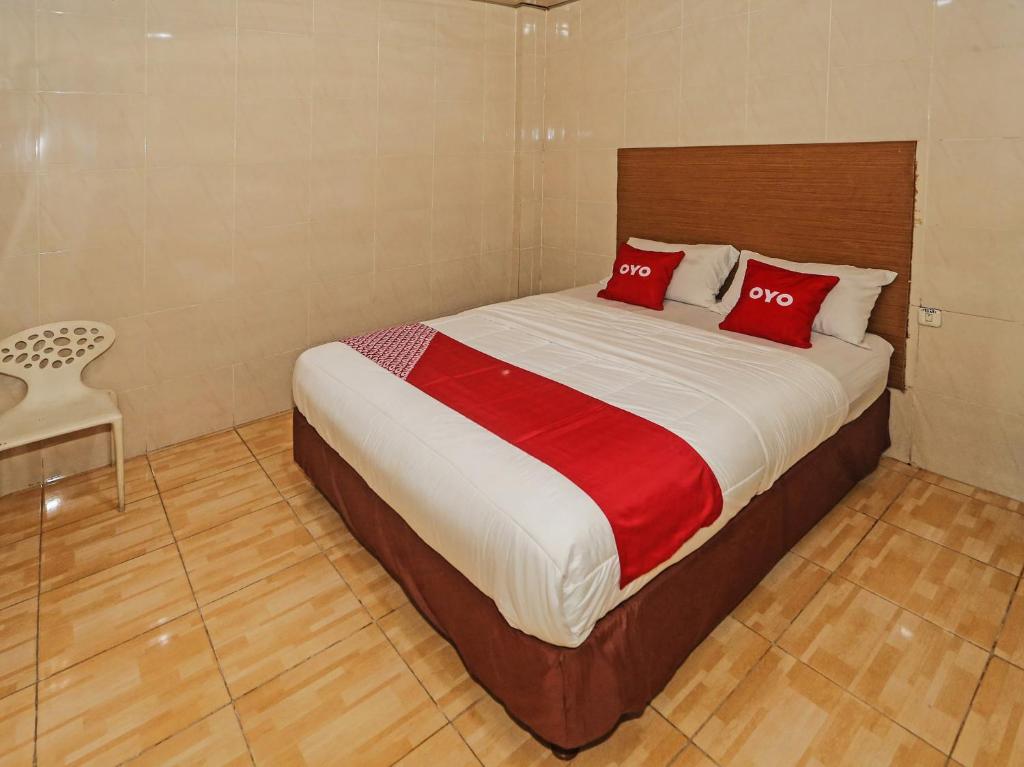 South TangerangOYO 92674 Hotel Ciputat的一间卧室配有一张带两个红色枕头的床