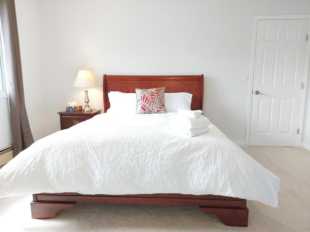 基洛纳Tranquil Retreat: Spacious 2-Bedroom Suite on a Serene Acreage的卧室配有白色的床和木制床头板
