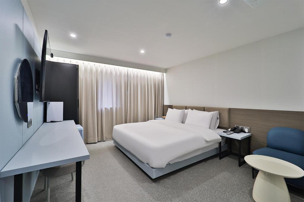 蔚山DOAN STAY HOTEL的酒店客房配有白色的床和蓝色椅子