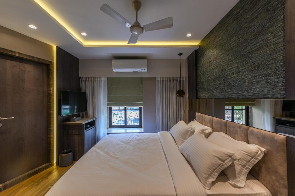 孟买Hotel Orient Regency的卧室配有一张白色大床和电视。
