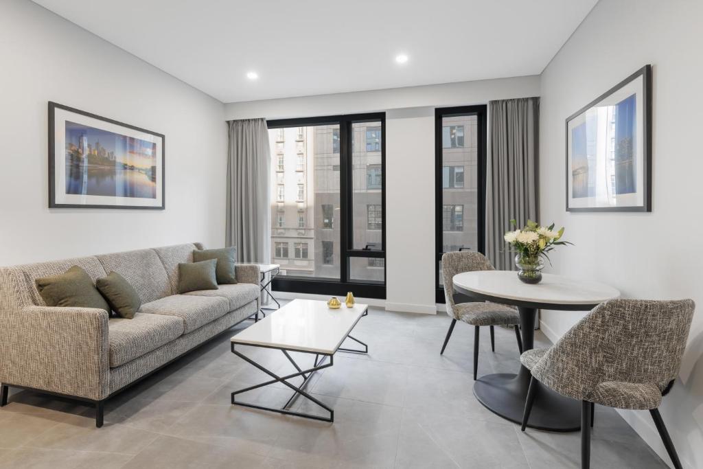 墨尔本Meriton Suites King Street Melbourne的客厅配有沙发和桌椅