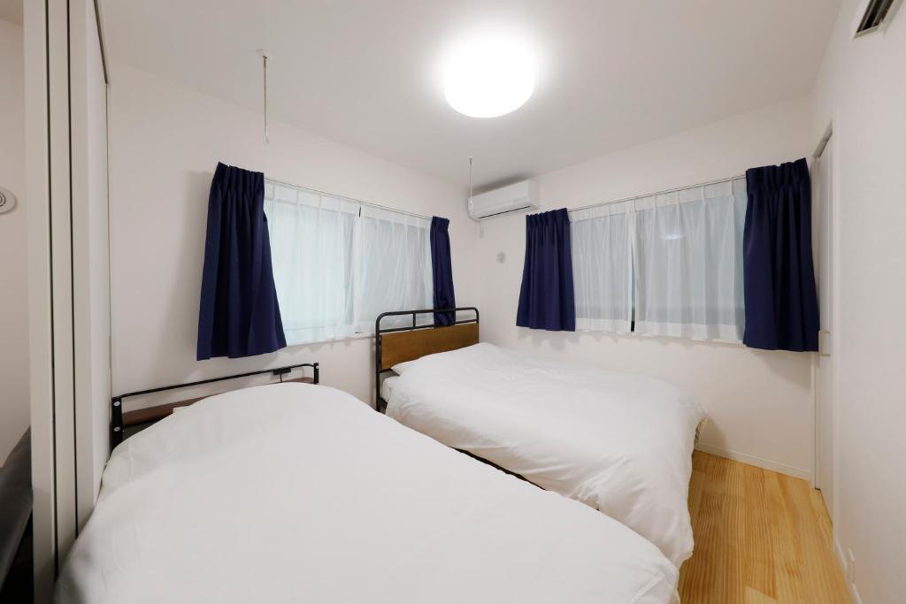 东京Setagaya House的小房间设有两张床,配有蓝色窗帘