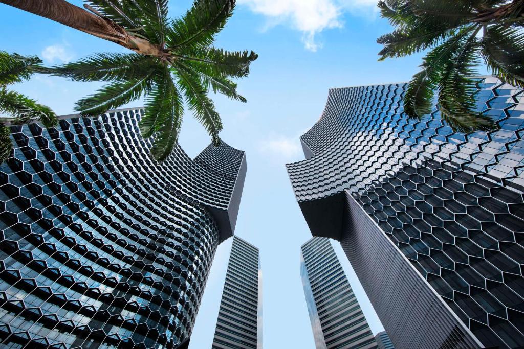 新加坡Andaz Singapore A Concept by Hyatt的两座高大的楼房,前方有棕榈树
