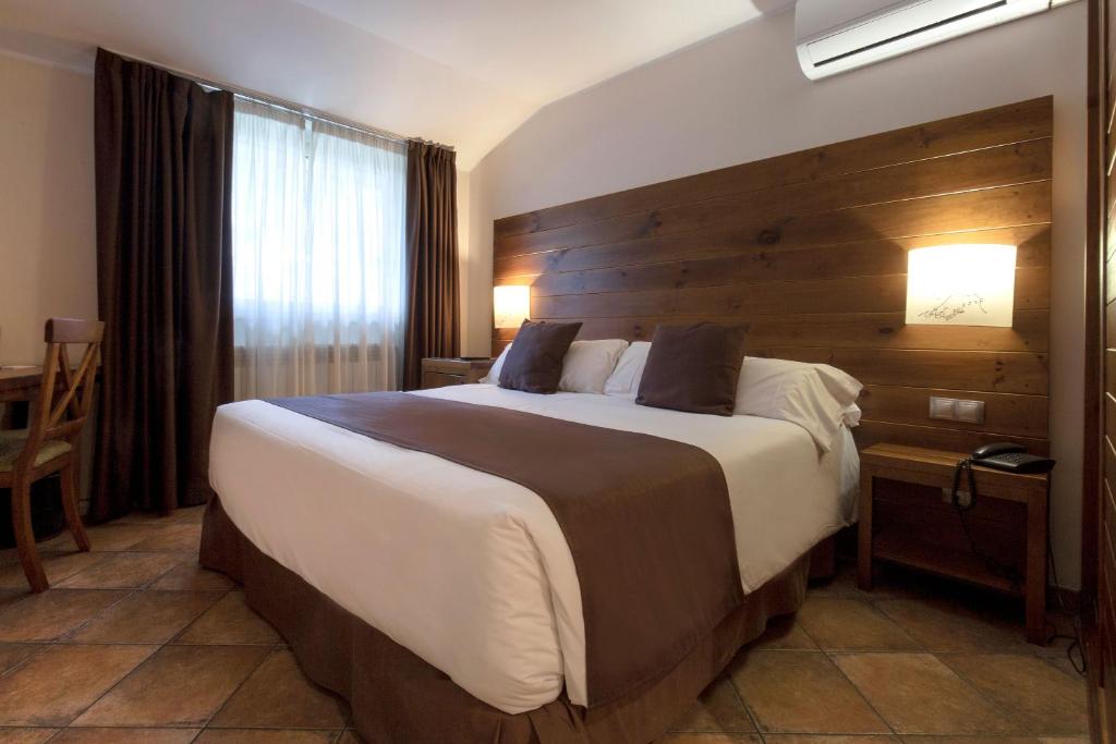 马萨纳Hotel Màgic La Massana的一间卧室设有一张带木墙的大床