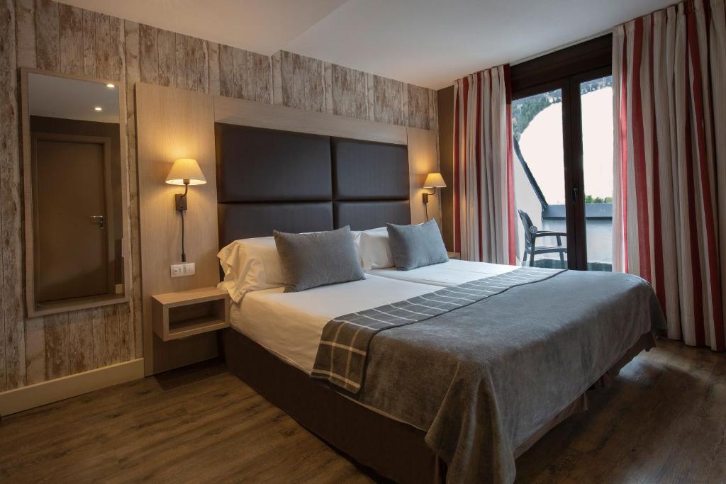 索尔德乌Hotel Himàlaia Soldeu的一间卧室设有一张大床和一个大窗户
