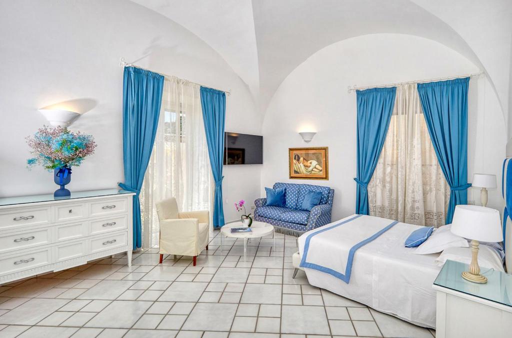 卡普里Le Botteghe 59 Capri的一间卧室配有蓝色窗帘、一张床和椅子