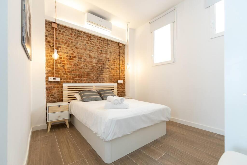 马德里Apartamento 1hab con estilo cerca de Ventas的卧室配有白色的床和砖墙